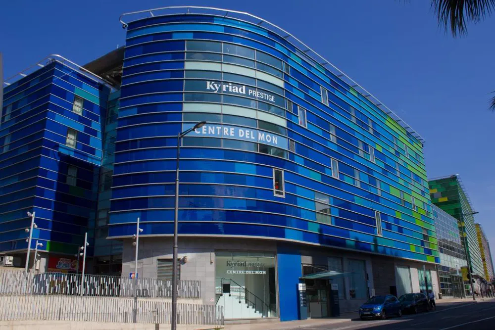 Fachada vidriada y azul del hotel Kyriad Prestige Centre del Mon en Perpiñán, arquitectura contemporánea junto a la estación.