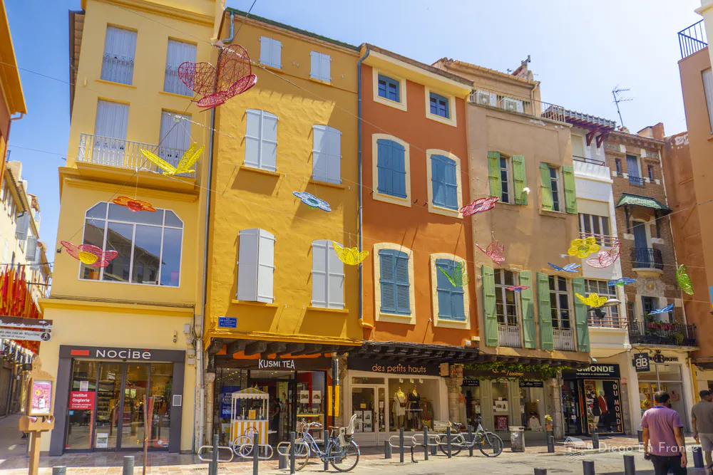 Calles del centro de Perpiñán con fachadas coloridas y decoración de verano, una imagen típica recomendada por diegoenfrance.com