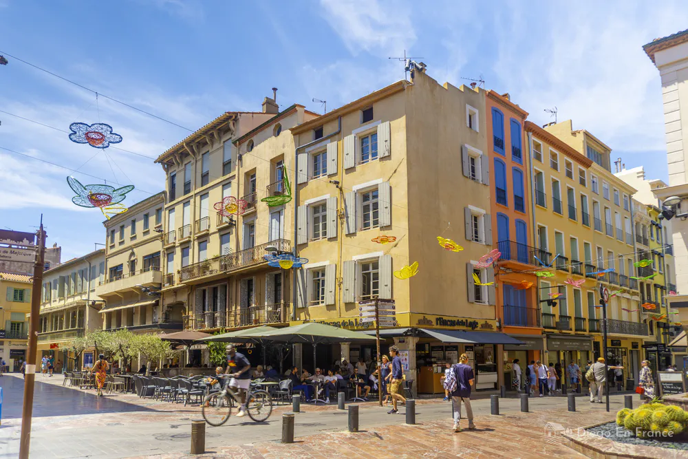 Fotografía de diegoenfrance.com de una calle comercial colorida, con tiendas, decoraciones y ambiente turístico en Perpiñán