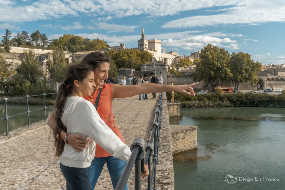 Fotografía de diegoenfrance.com mostrando a dos personas contemplando el Palacio de los Papas desde el Puente Saint-Bénézet, ideal para quienes buscan qué hacer en Aviñón