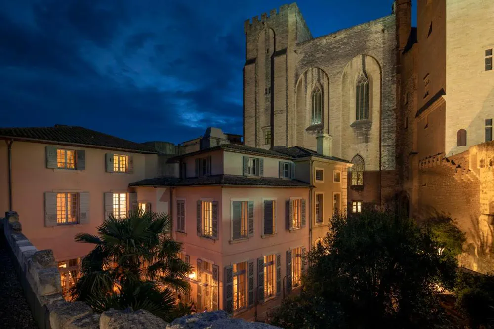 Mostrando el Hotel La Mirande iluminado al anochecer, ideal para quienes buscan qué hacer en Aviñón con estilo y encanto histórico